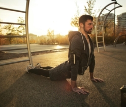 A man doing yoga in a park during sunrise, highlighting fitness and a healthy lifestyle.