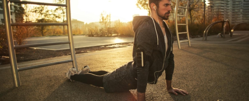 A man doing yoga in a park during sunrise, highlighting fitness and a healthy lifestyle.