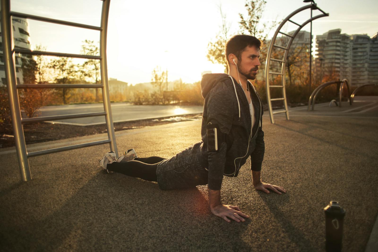 A man doing yoga in a park during sunrise, highlighting fitness and a healthy lifestyle.