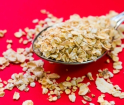 Close-up image of oats scattered on a spoon with vivid red background, perfect for food advertising.