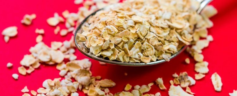 Close-up image of oats scattered on a spoon with vivid red background, perfect for food advertising.